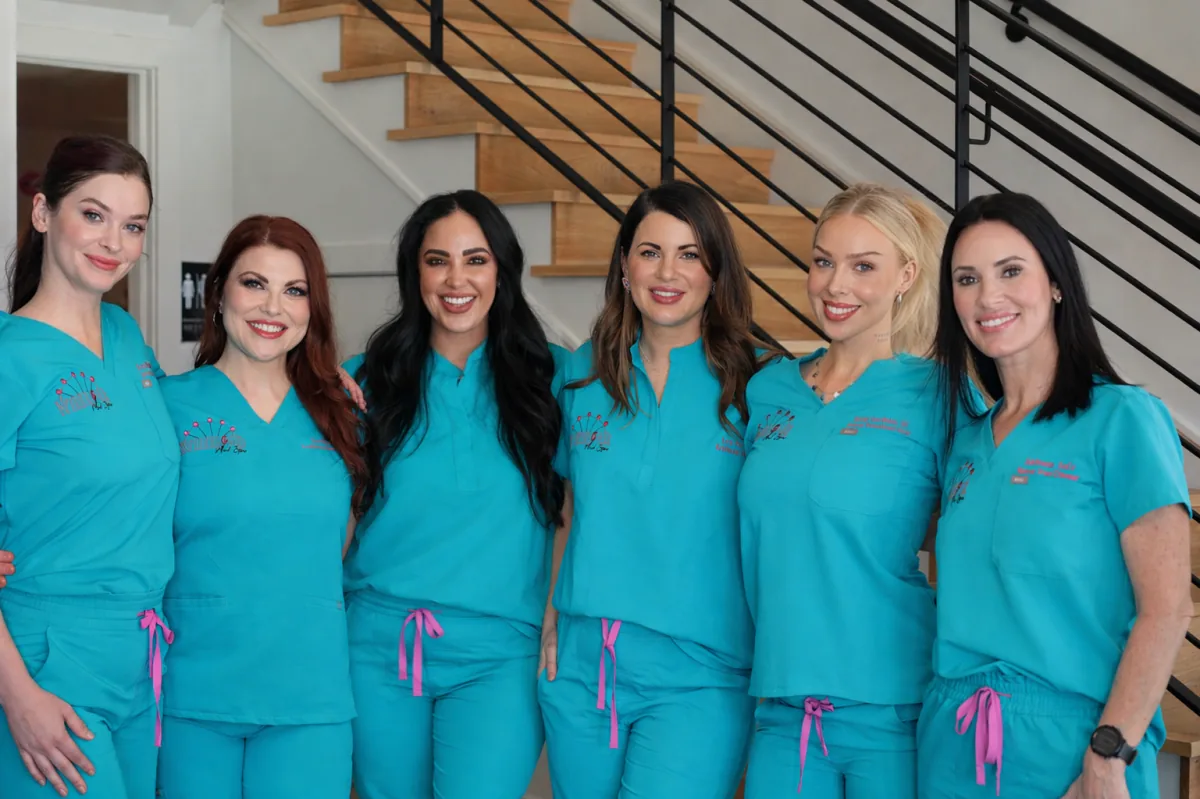 The Wheeler Med Spa team in teal scrubs on the staircase inside the spa