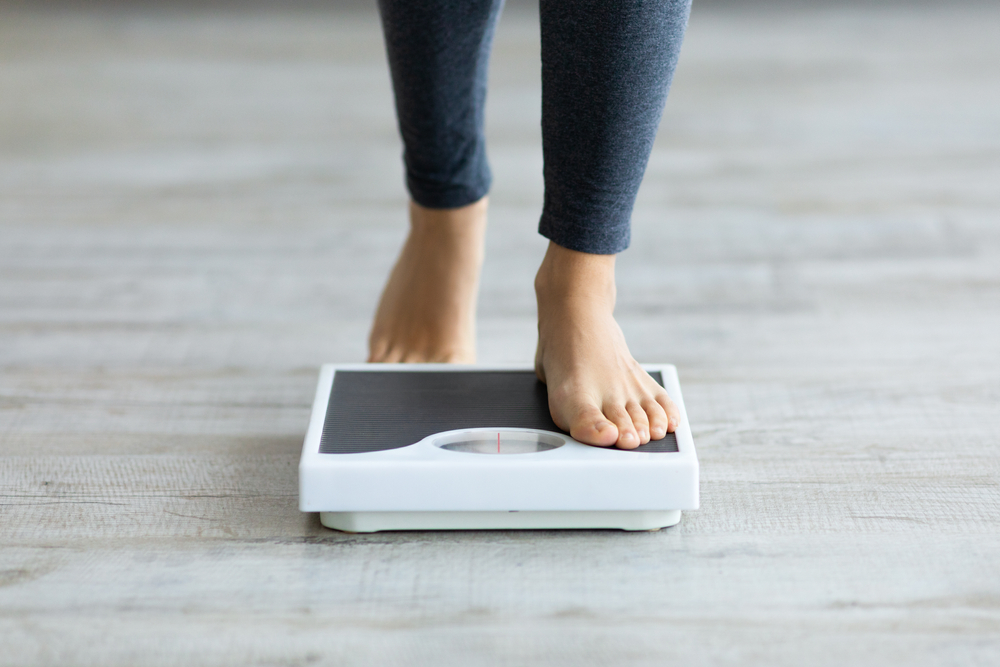 Close-up of a woman's feet as she steps onto a scale to measure her personalized weight-loss progress. Close-up of a woman's feet as she steps onto a scale to measure her personalized weight-loss progress.